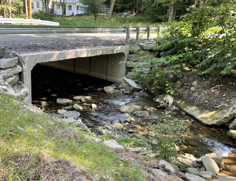 Box culvert and stone rip-rap carrying water under a drive